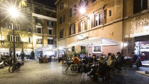An outdoor café with tables and chairs, surrounded by buildings with balconies and windows. - Casa de' Fiori Biscione (Rome)