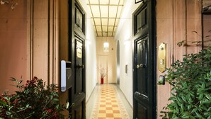 A hallway with checkered flooring, black doors, and a potted plant. - Casa de' Fiori Biscione (Rome)