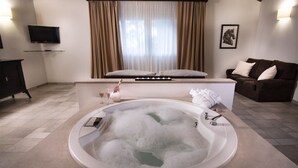 Ein modernes Badezimmer mit freistehender Badewanne, einem Waschtisch mit Spiegel und einer Couch im angrenzenden Wohnbereich.