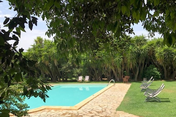 Una piscina al aire libre de temporada, sombrillas