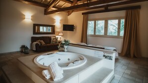 Ein geräumiges Badezimmer mit einer großen Badewanne, einer Sitzecke und einem Fenster mit Vorhängen.