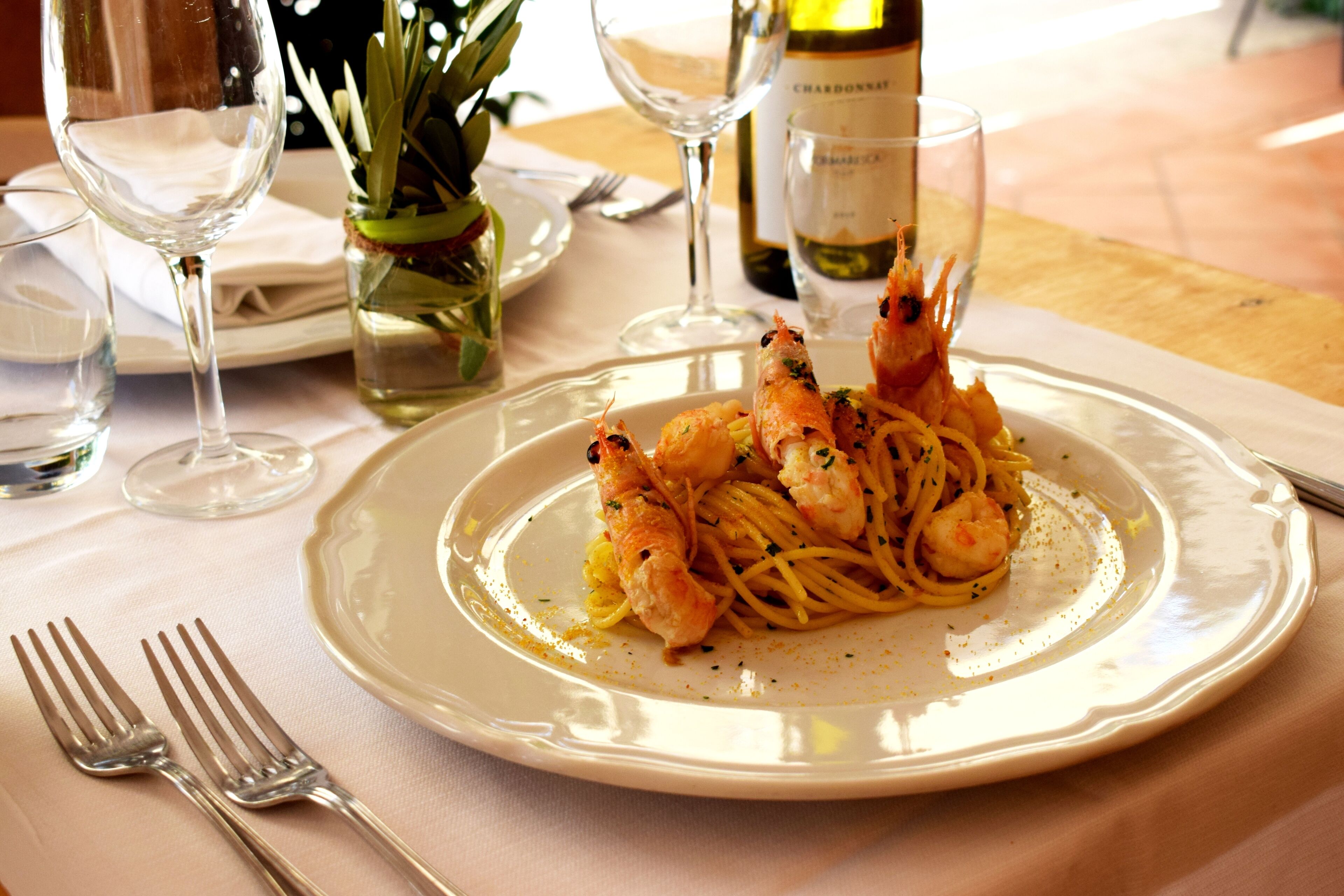 A plate of pasta with shrimp on a white tablecloth.