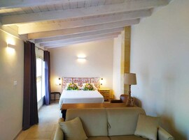 Una habitación de hotel con cama, sofá, mesita de noche y lámpara.