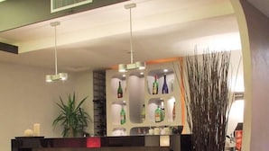 Une cuisine moderne dotée d’un coin bar, avec un îlot central agrémenté de tabourets, d’un éclairage suspendu et d’une plante décorative.