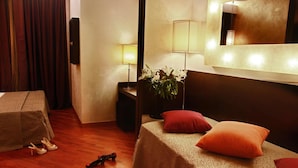 Une chambre d’hôtel avec un lit, une table de chevet, une lampe, un miroir et une plante.