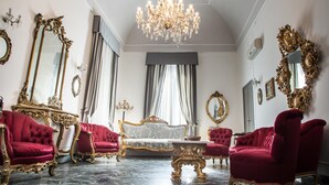 A luxurious room with ornate furniture, a chandelier, and large mirrors. - Palazzo Angelelli (Gallipoli)