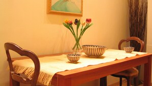 Ein Esstisch mit einer Tulpenvase, zwei Schüsseln und einem Baumgemälde an der Wand.