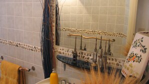 Ein Badezimmer mit Waschbecken, Spiegel und Dekoelementen, darunter ein Handtuchhalter und ein Spiegel mit Zierleiste.