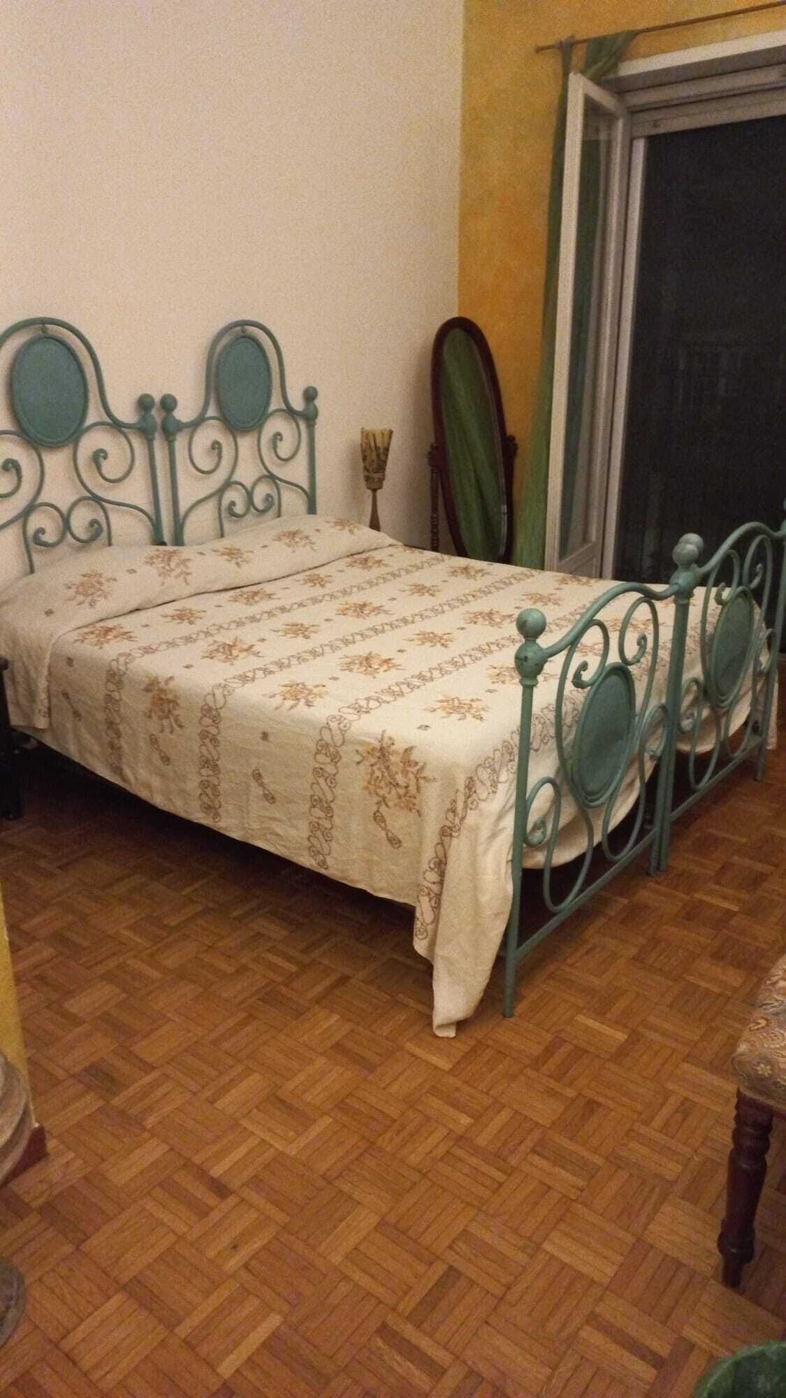 Ein Bett mit einem gemusterten Überwurf in einem Zimmer mit Holzdielenboden.