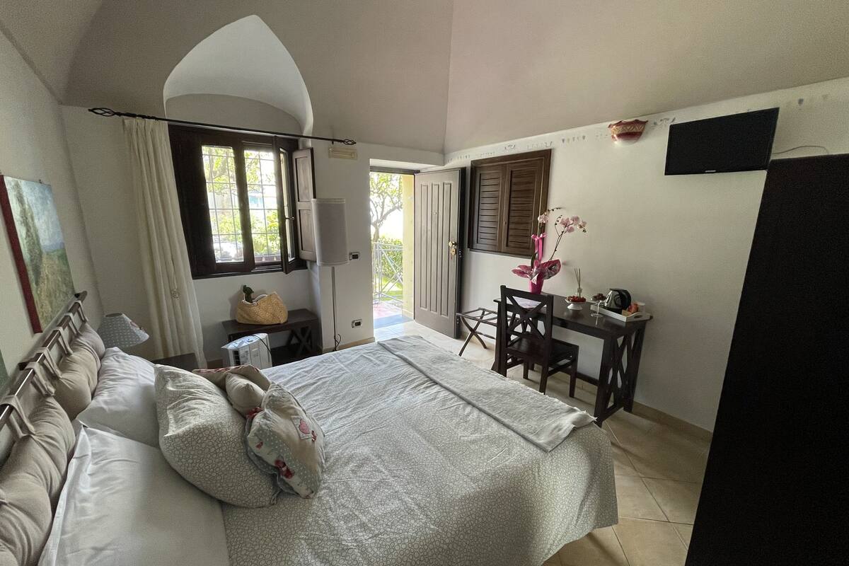 Ein Schlafzimmer mit Bett, Schreibtisch, Stuhl, Fenster und Tür.