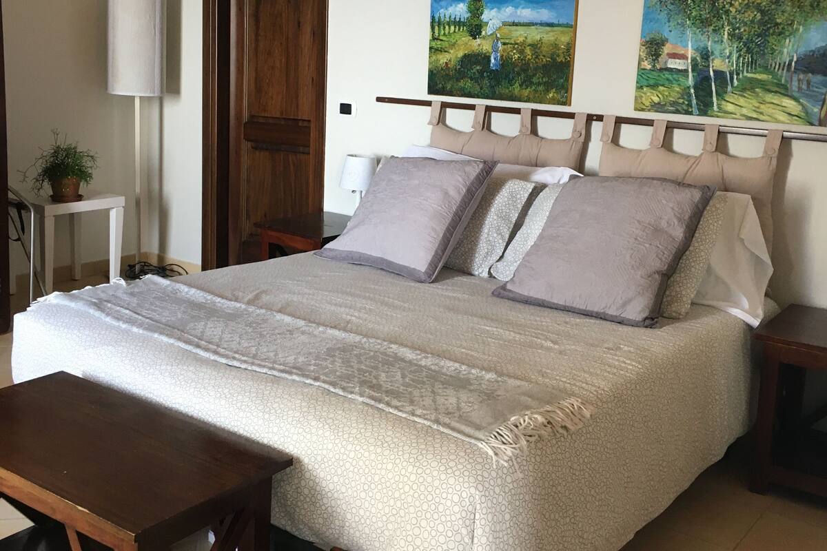 Ein Schlafzimmer mit einem Bett, Nachttischen, einer Lampe und zwei Bildern an der Wand.