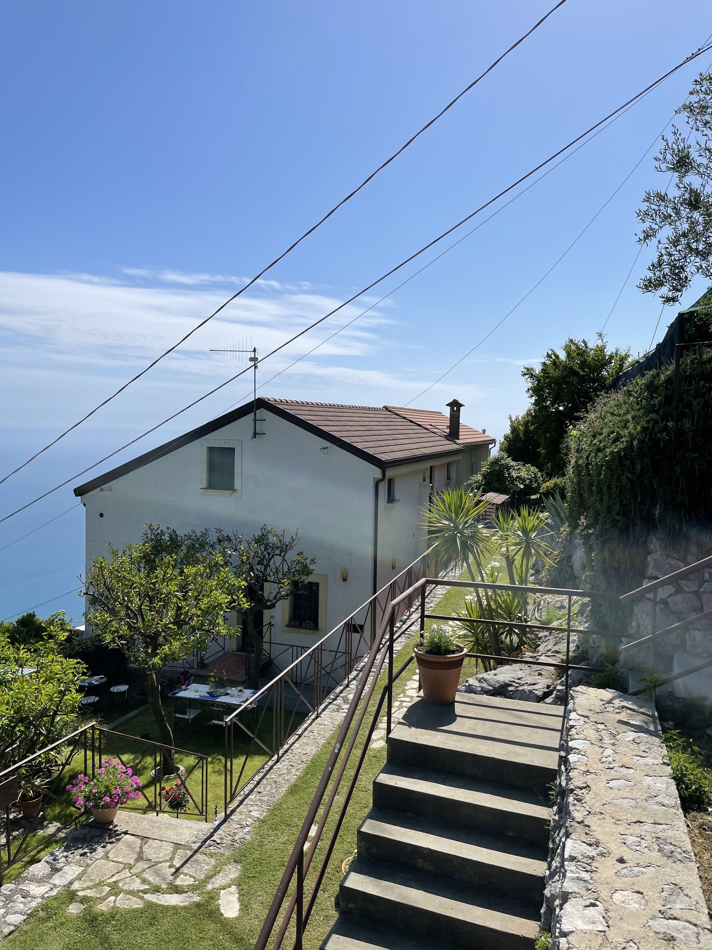 Une maison blanche avec un toit rouge, un escalier en pierre et une vue sur la mer.