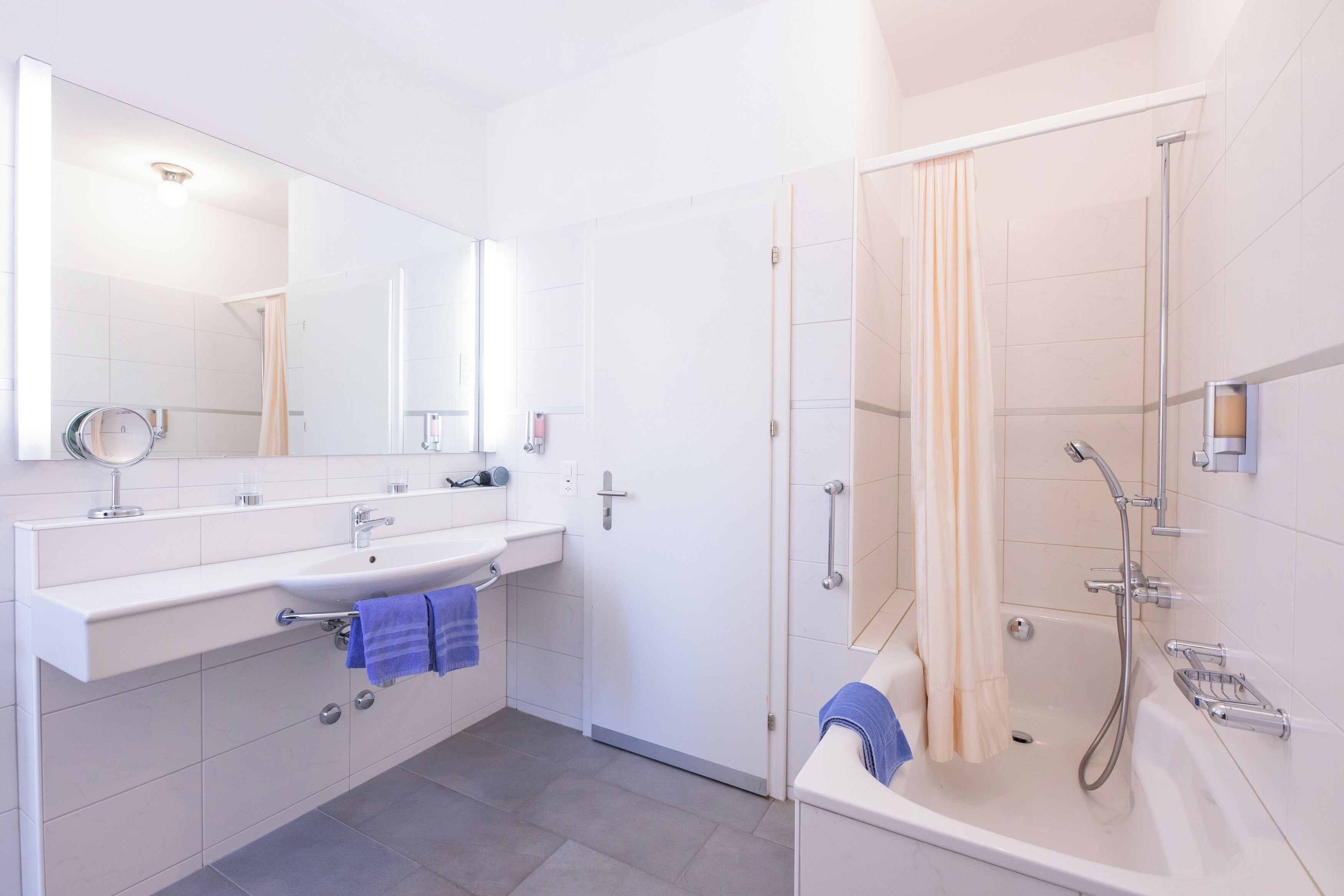 Un baño moderno con un espejo grande, un lavabo, una ducha y una bañera.