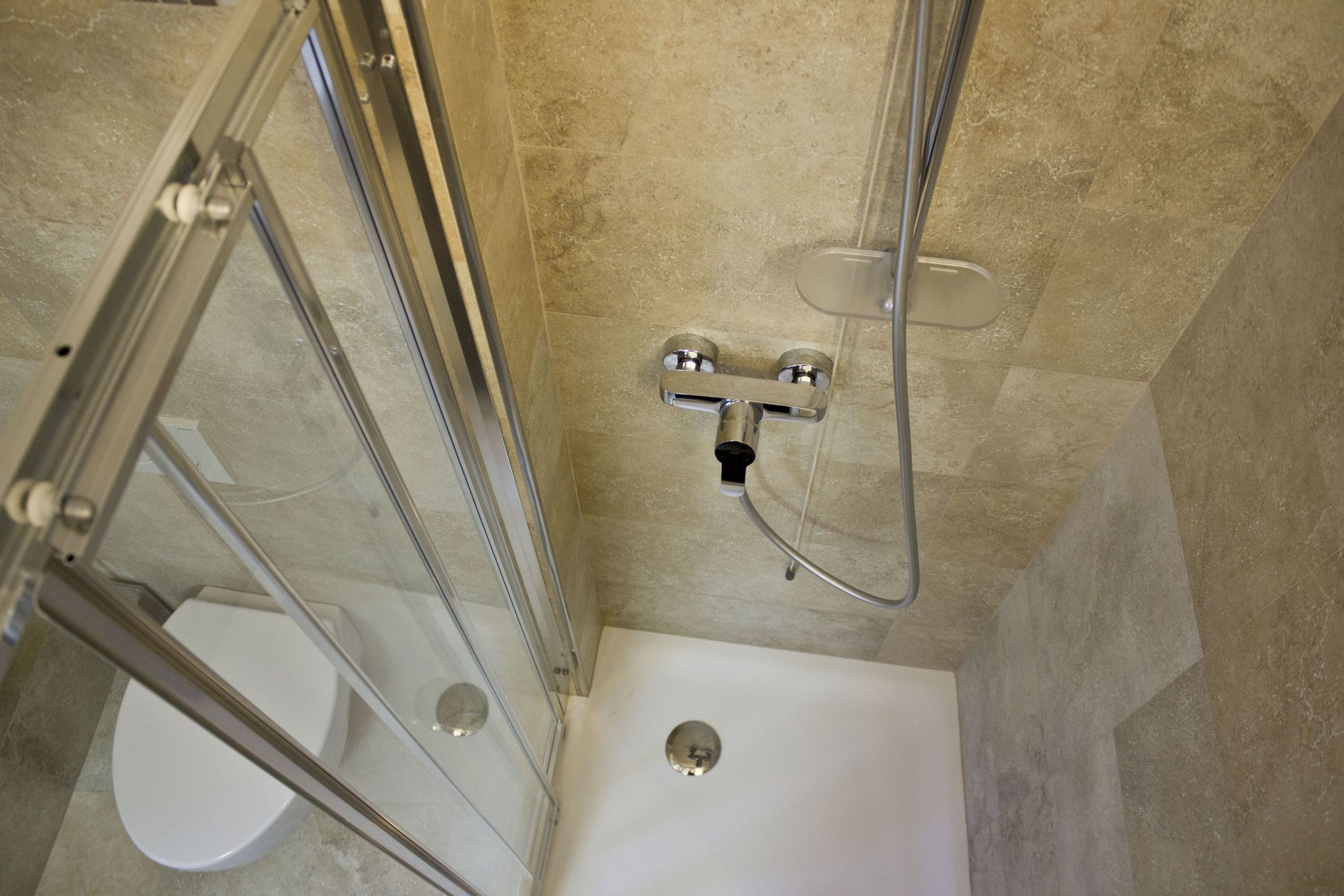 A shower with a glass door, a white toilet, and a bathtub.