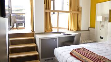 Ein Hotelzimmer mit Bett, Schreibtisch und einem fenster mit Vorhängen.