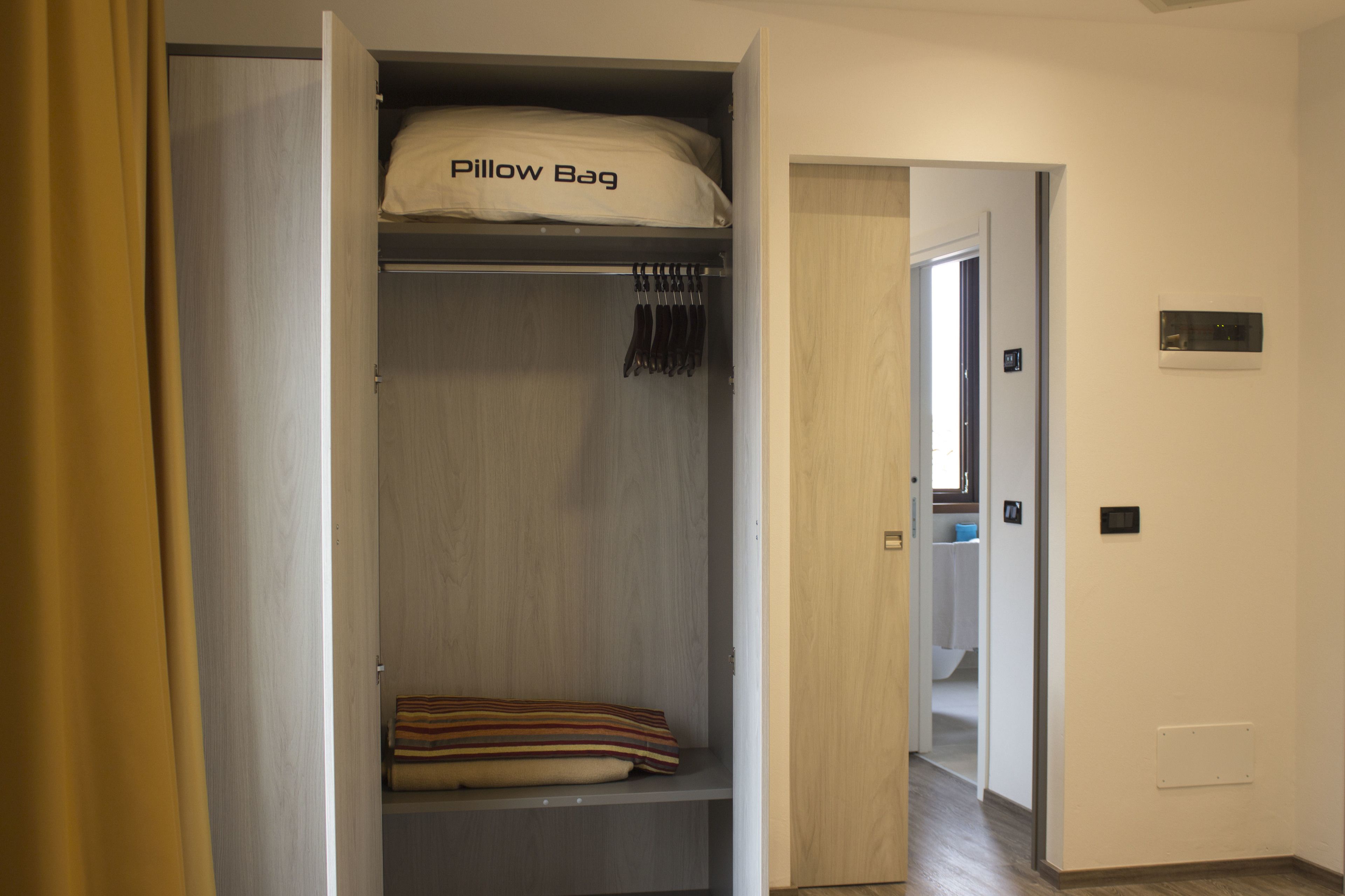 Un vestidor con una percha y una bolsa para almohadas etiquetada como "Pillow Bag" en el estante superior.