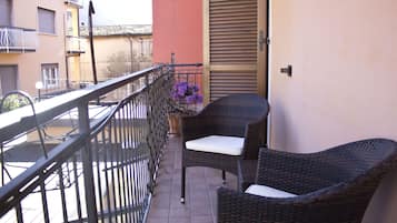 A balcony with wicker furniture and a potted plant.