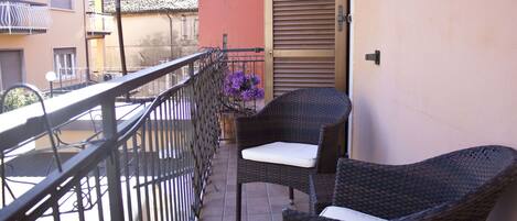 A balcony with wicker furniture and a potted plant.