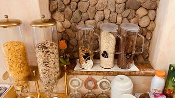 Zona cuina amb diferents recipients per guardar aliments, incloent pots i dosificadors, i una paret de pedra al fons.
