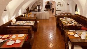 Un restaurante con mesas y bancos de madera, piso de espiga y pared de piedra al fondo.