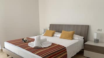 A neatly made bed with a striped bedspread, two pillows, and a rolled towel.