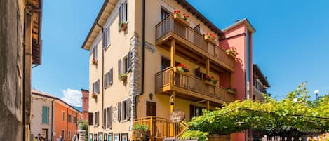 Un hotel con balcón, mobiliario exterior y un letrero que indica que es un hotel.
