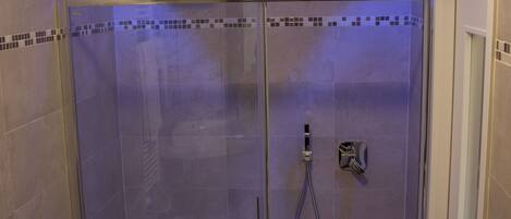 A walk-in shower with a glass door, tiled walls, and a small shelf above the shower.