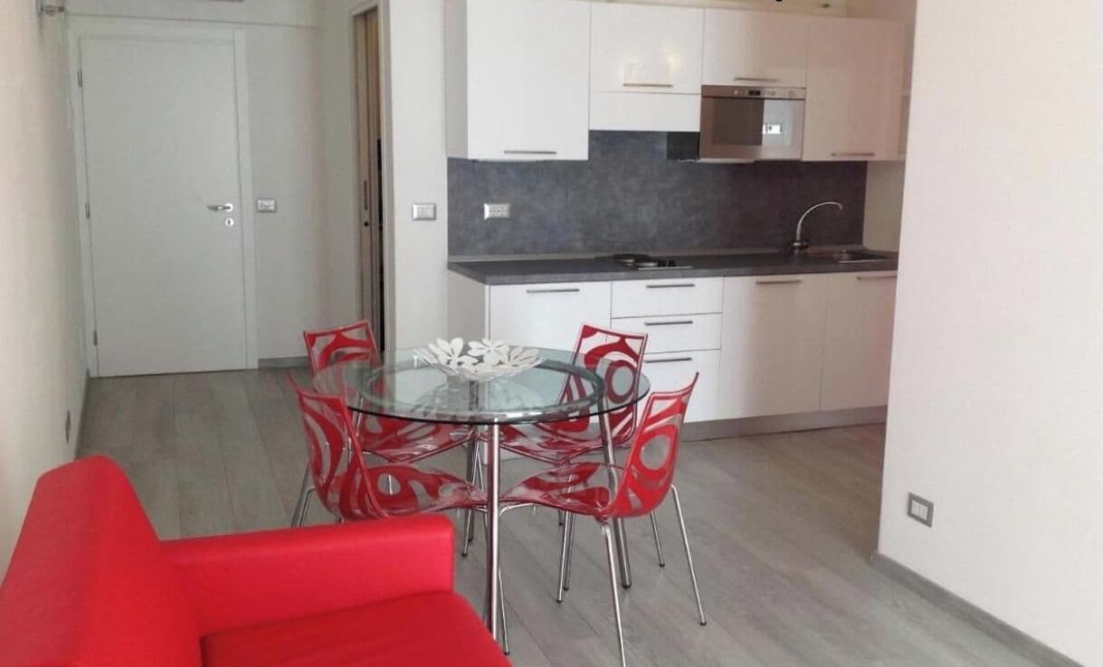 A compact kitchen with white cabinets, a black countertop, and a stainless steel sink.