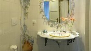 Egy fürdőszoba, amelyben WC, mosdókagyló és tükör található.