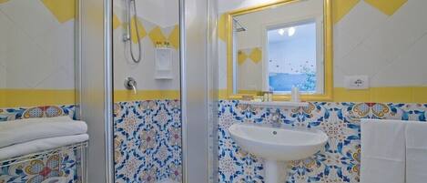 Une salle de bain avec une douche, un lavabo et un miroir.