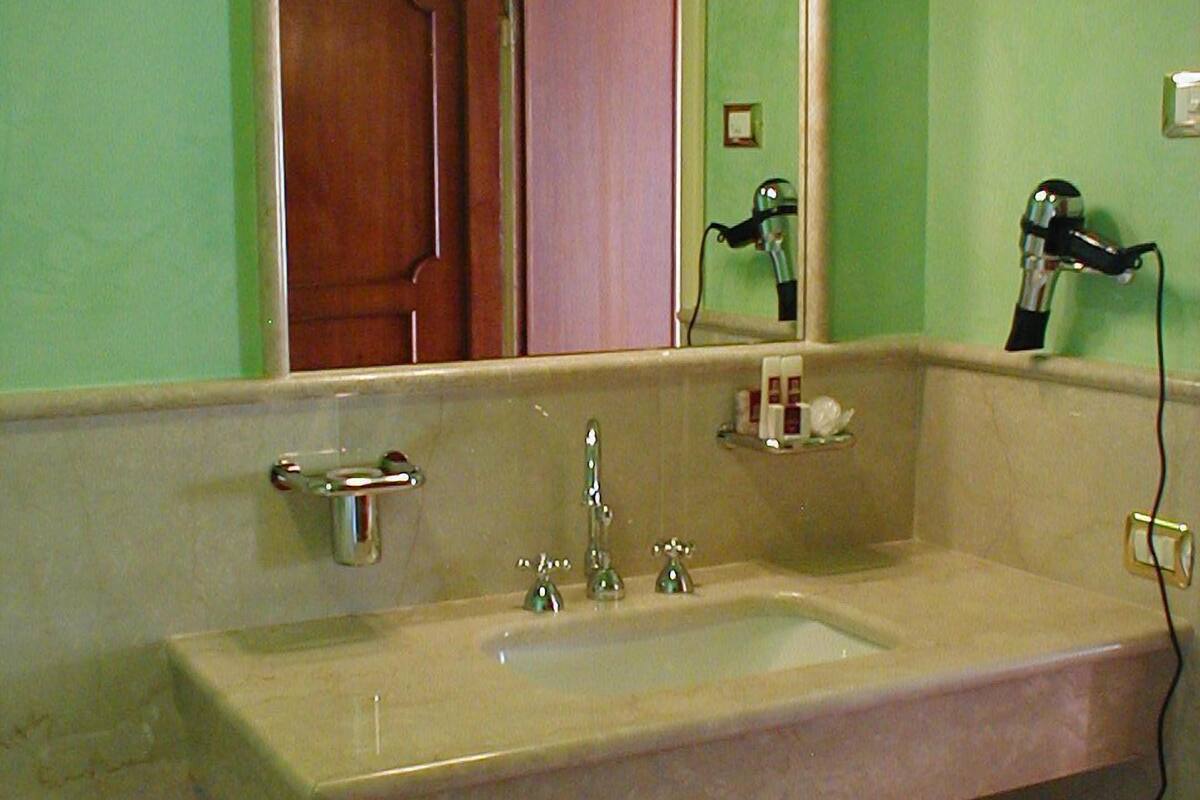 Un baño con lavamanos, espejo y secador de pelo.