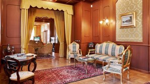 Une pièce de style traditionnel avec un mur lambrissé en bois, un tapis à motifs et des meubles classiques, notamment un canapé et des fauteuils.