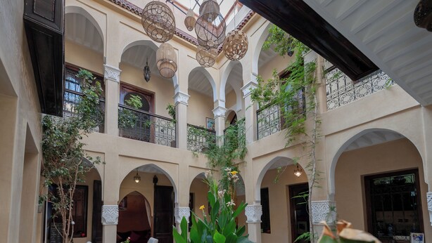 A multi-level courtyard with arches, hanging lanterns, and potted plants.