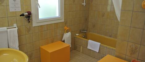 A bathroom with a yellow sink, a bathtub, and a window.