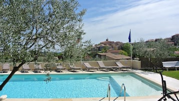 Una piscina al aire libre, sillones reclinables de piscina