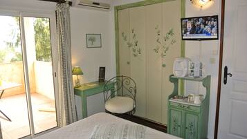 Un dormitorio con cama, una silla, un escritorio, un televisor y un armario.