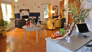 Una sala de estar acogedora con un sofá, una mesa redonda con botellas, una computadora portátil y una planta en maceta.