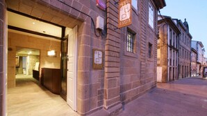A hotel entrance with a stone facade, a reception desk, and a sign indicating a parking area. - A Tafona do Peregrino (Santiago de Compostela)