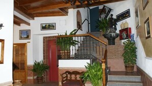 A staircase with a wooden handrail, a red door, and potted plants. - Juan Francisco (Guejar Sierra)