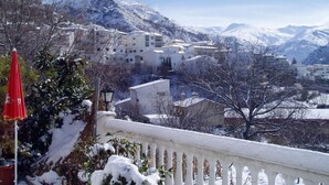 A snow-covered mountain village with buildings and a red umbrella in the foreground. - Juan Francisco (Guejar Sierra)