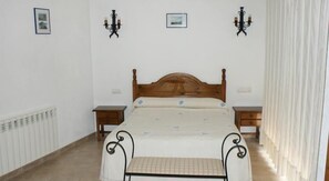 Une chambre à coucher avec un lit en bois, deux tables de chevet, un radiateur et deux lampes fixées au mur.
