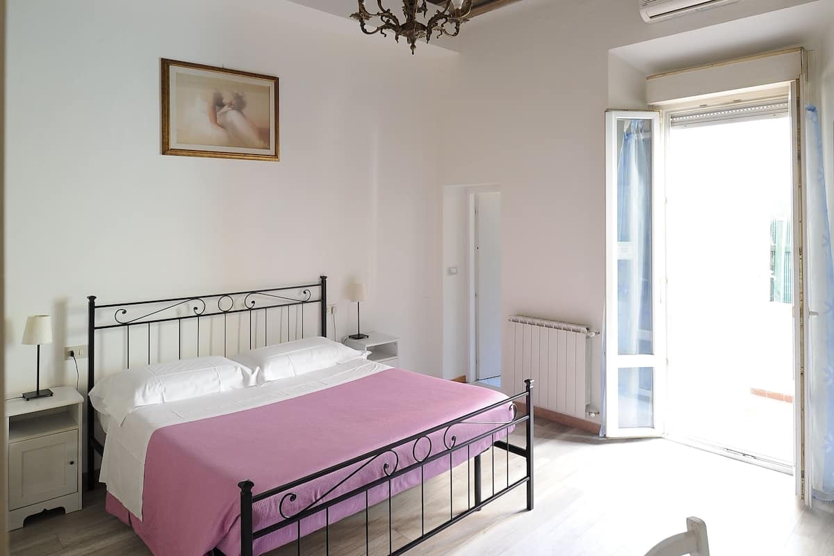 Un dormitorio con cama, candelabro, radiador y puerta que da a un balcón.