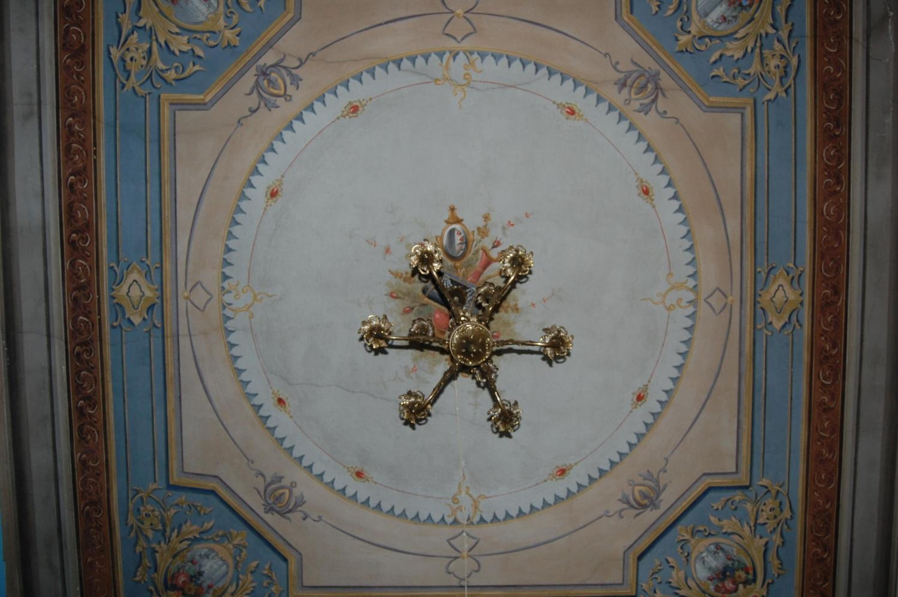 A ceiling with a decorative central medallion and ornate patterns.