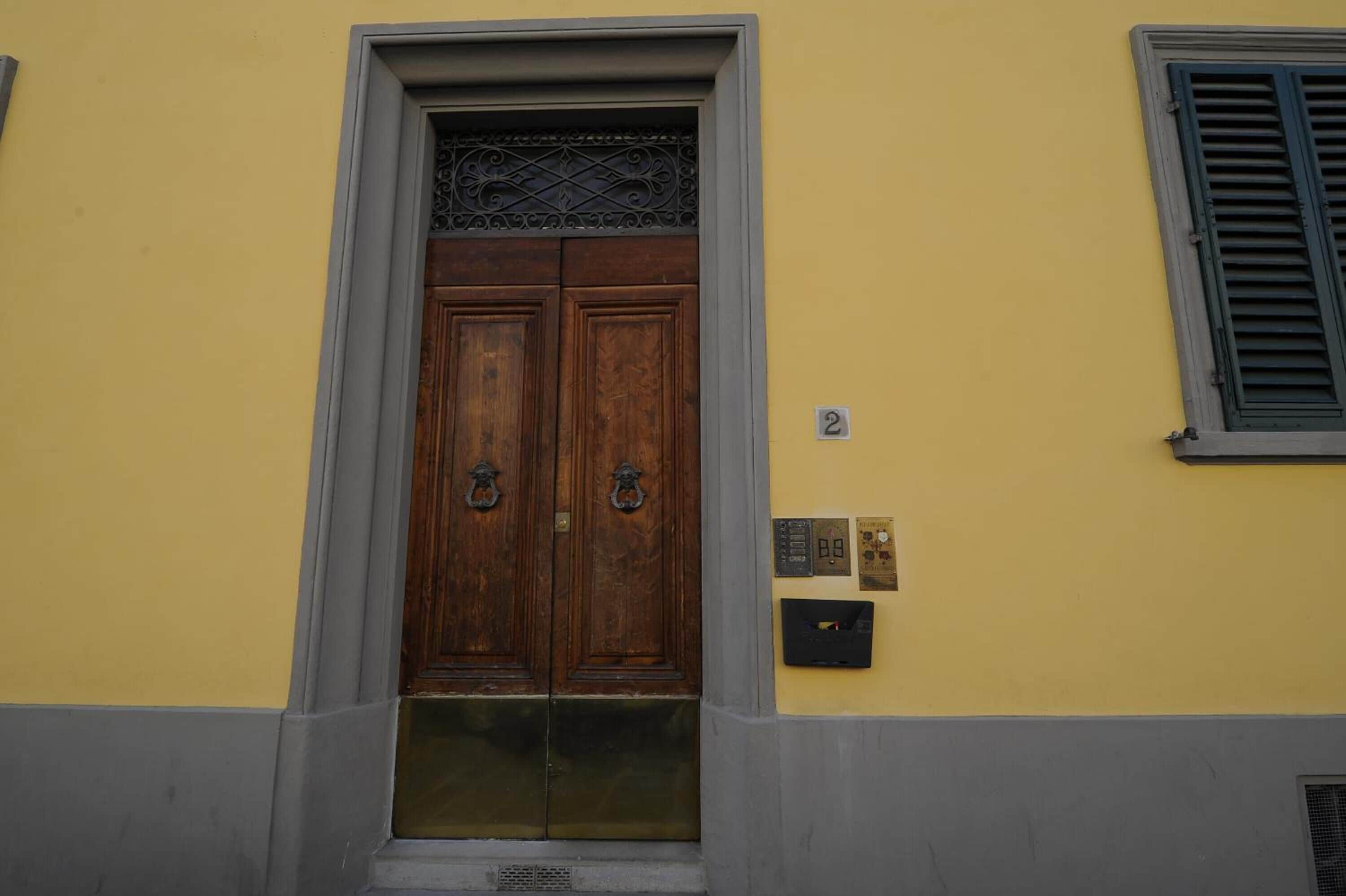 Un edificio amarillo con una puerta doble de madera y un buzón pequeño en la pared.