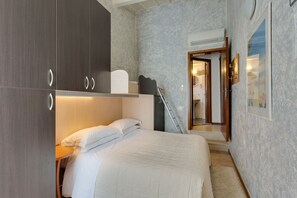 A bedroom with a bed, a wardrobe, a desk, and a bathroom visible through an open door. - Affittacamere Casa Billi (Florence)