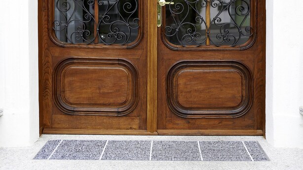 Una puerta doble de madera con detalles de hierro forjado y un panel de vidrio.