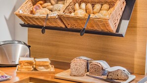 Una presentación de desayuno con pan y bollería, un tostador y una pizarra con saludos en varios idiomas.