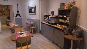 A dining area with tables, chairs, a buffet counter, and a bookshelf with books and decorative items. - Hotel Regyn's Montmartre (Paris)