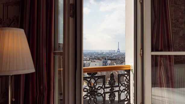 A view from a balcony with a wrought iron railing, overlooking a cityscape with the Eiffel Tower in the distance. - Hotel Regyn's Montmartre (Paris)