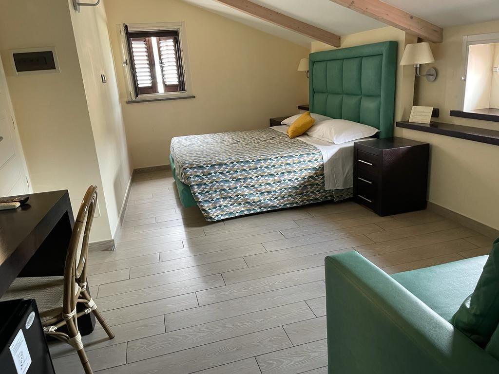 A bedroom with a bed, bedside table, lamp, and a window.
